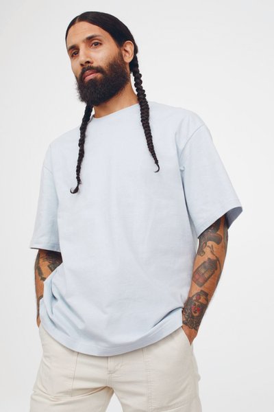 Man long braid pale blue tshirt beige chino trousers