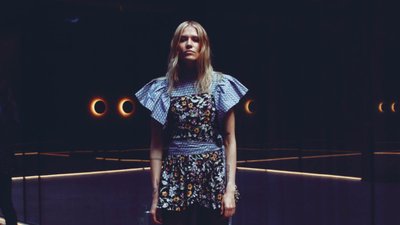 Woman standing in a dark space with mirrors behind her