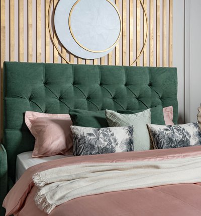 Green velvet bed headboard and scattered cushions