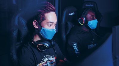 Two men face masks headphones playing esport game