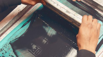 A squeegee applying dye to a silkscreen