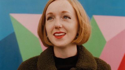 Close up woman brown wool coat colourful artwork background