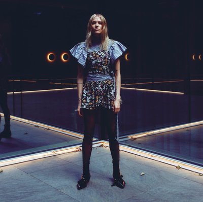 Woman standing in a dark space with mirrors behind her