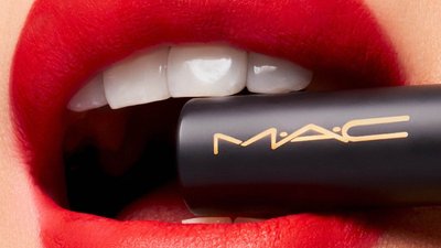 Woman with red lipstick with lipstick case in mouth
