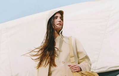 A woman wearing a Uniqlo U hooded coat and shirt, holding a drawstring bag